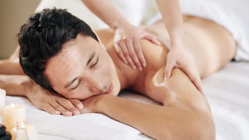 Massage therapist discreetly draping client's back with sheet