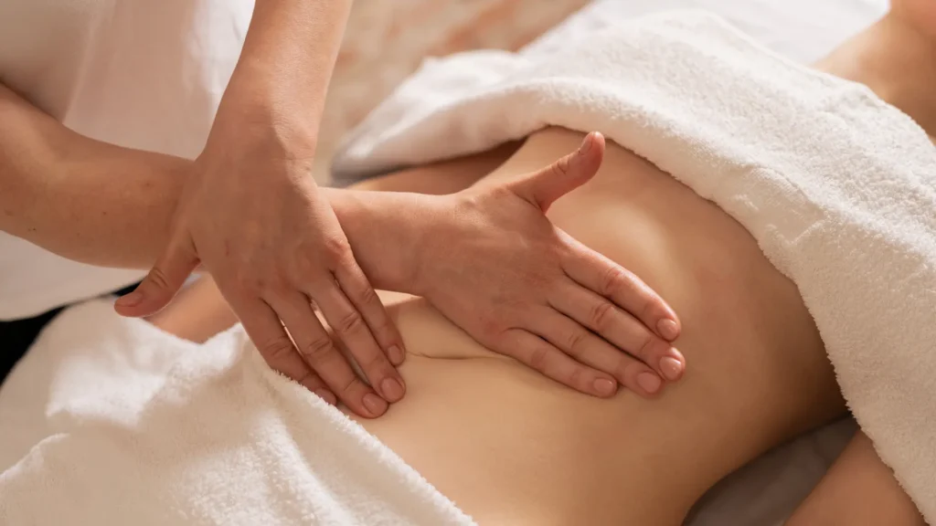 Woman relaxing while massage therapist adjusts draping sheet